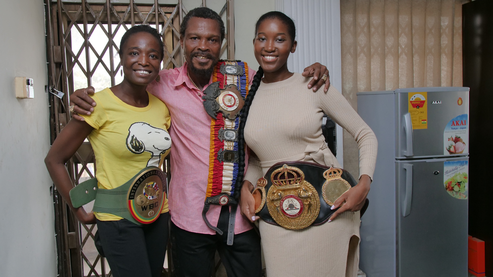 2 women flank a man, all holding boxing championship belts