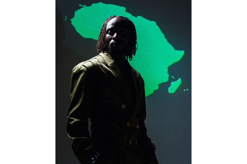 A dim picture of Fuse ODG posing behind a green background featuring the map of Africa.