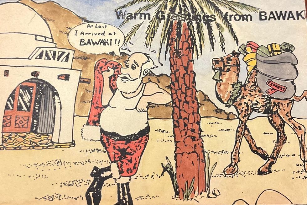 A drawing of Santa Claus leaning on a palm tree, with a camel carrying his gifts behind him. A speech bubble reads: "At last I arrived at Bawaki!!"