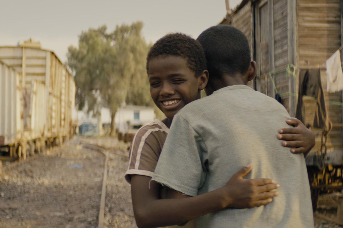 A film still of a boy hugging another boy