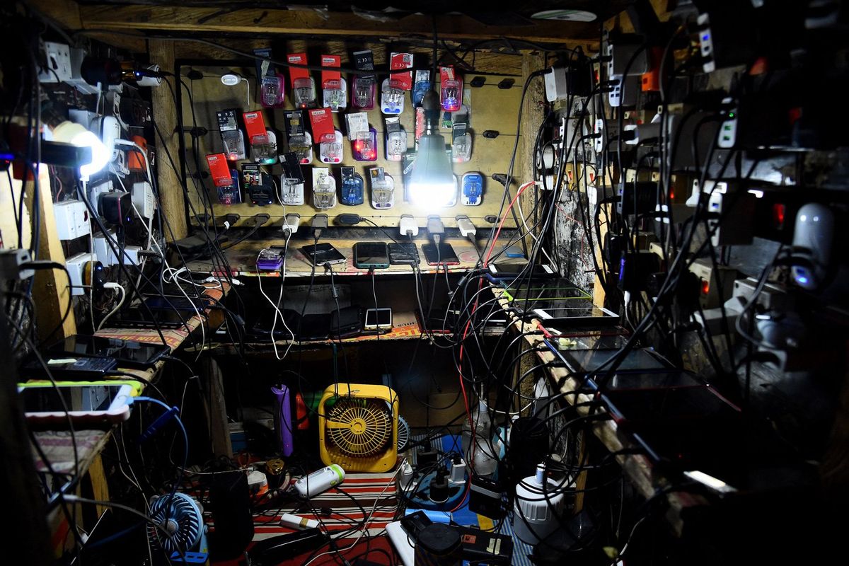 A general view of a shop with dozens of phones of clients without electricity being charged with multiple chargers at night at Ojodu district of Lagos on March 22, 2022.