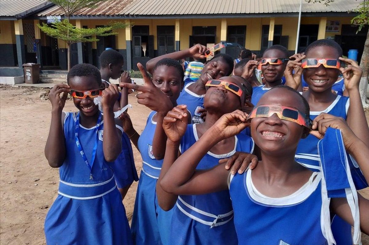 A group of children look up at the sky through 3D glasses