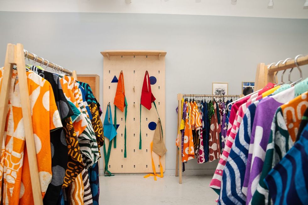 A hallway featuring wooden hangers filled with brightly colored clothes.