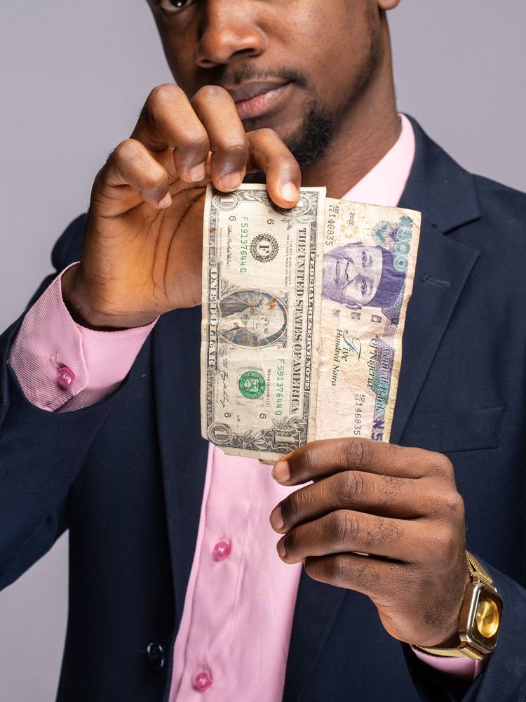 A man holding Naira and Dollar bills.