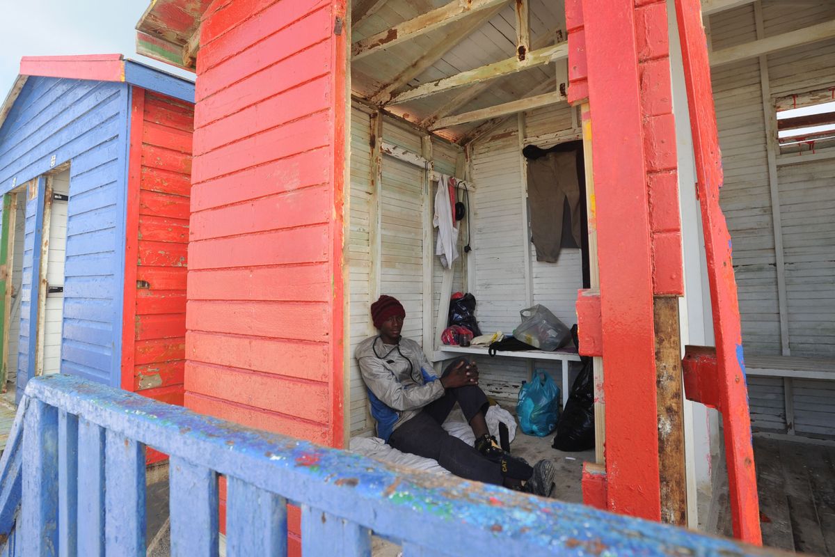 A man sits in an empty beach hut painted red in Cape Town, South Africa