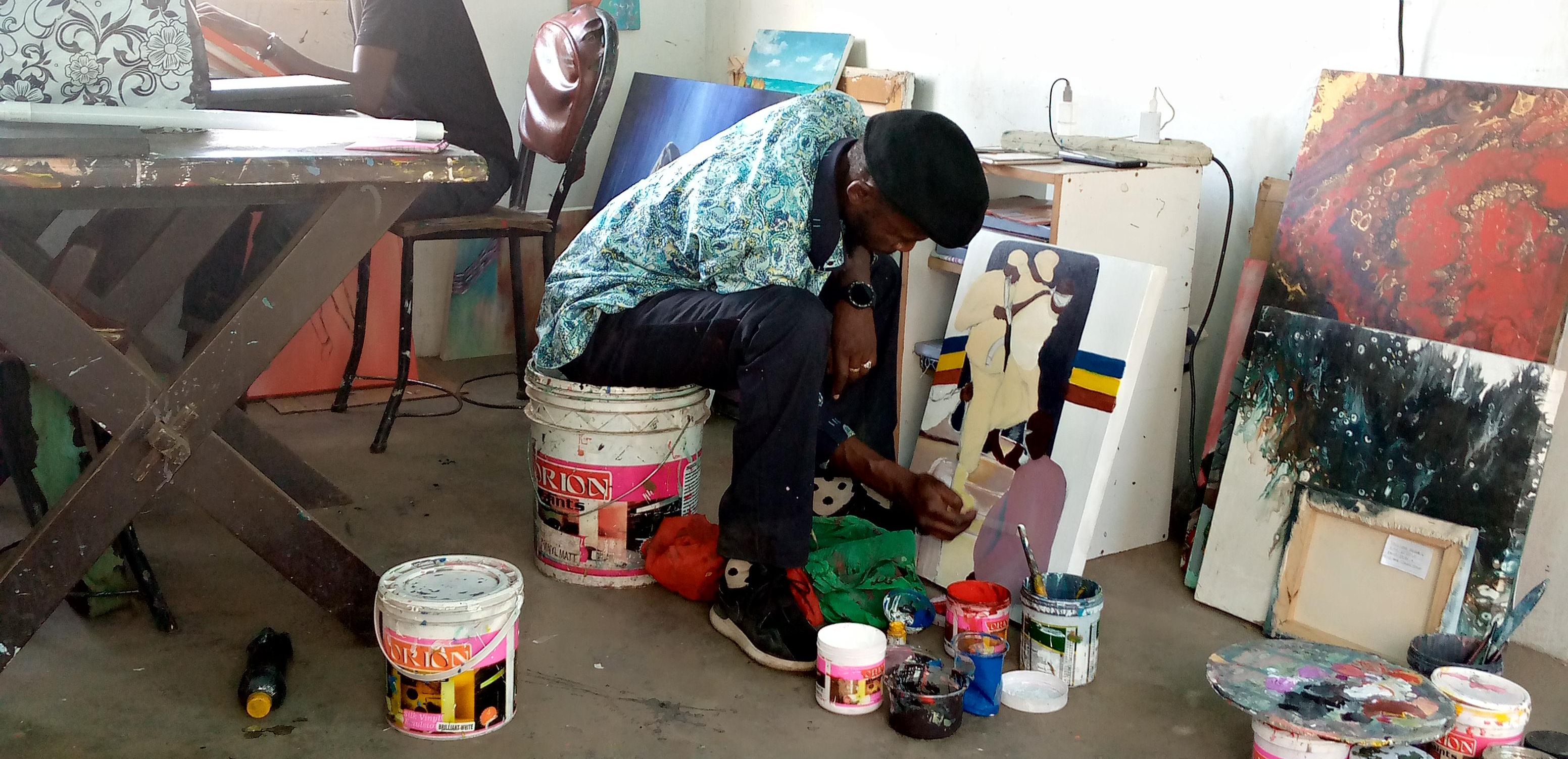 A man sitting on a bucket, painting