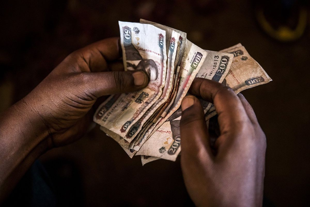 A market trader counts Kenyan shilling banknotes