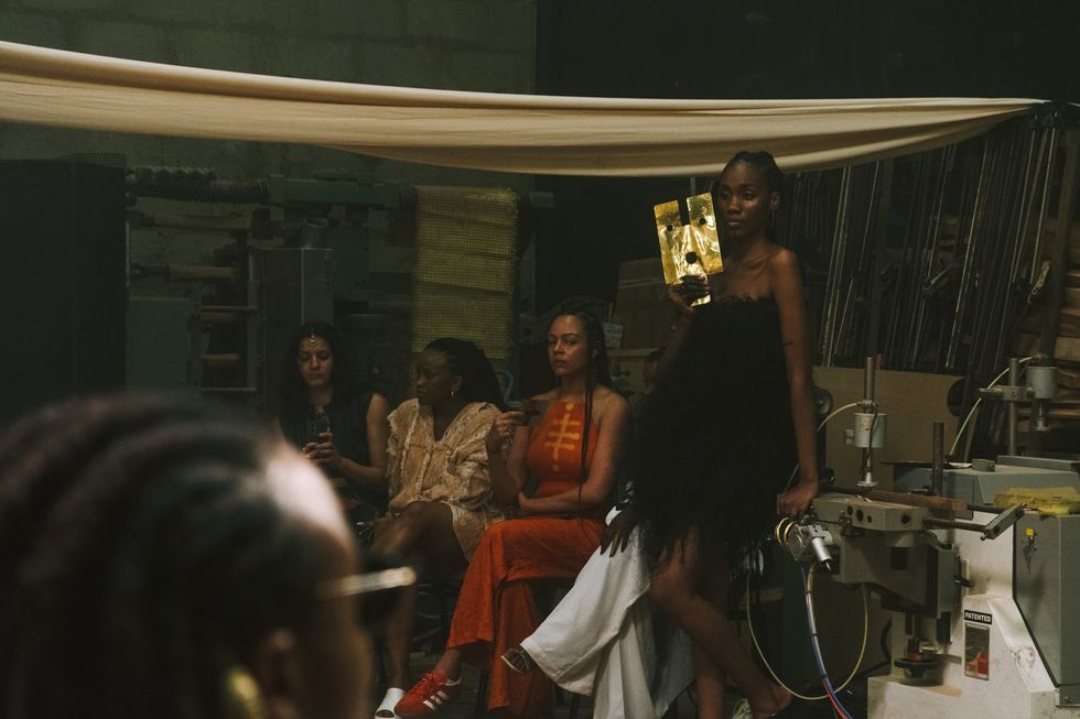 A model holds up a brass mask at the IAMISIGO SS24 runway show during Lagos Fashion Week 2023 (offsite).