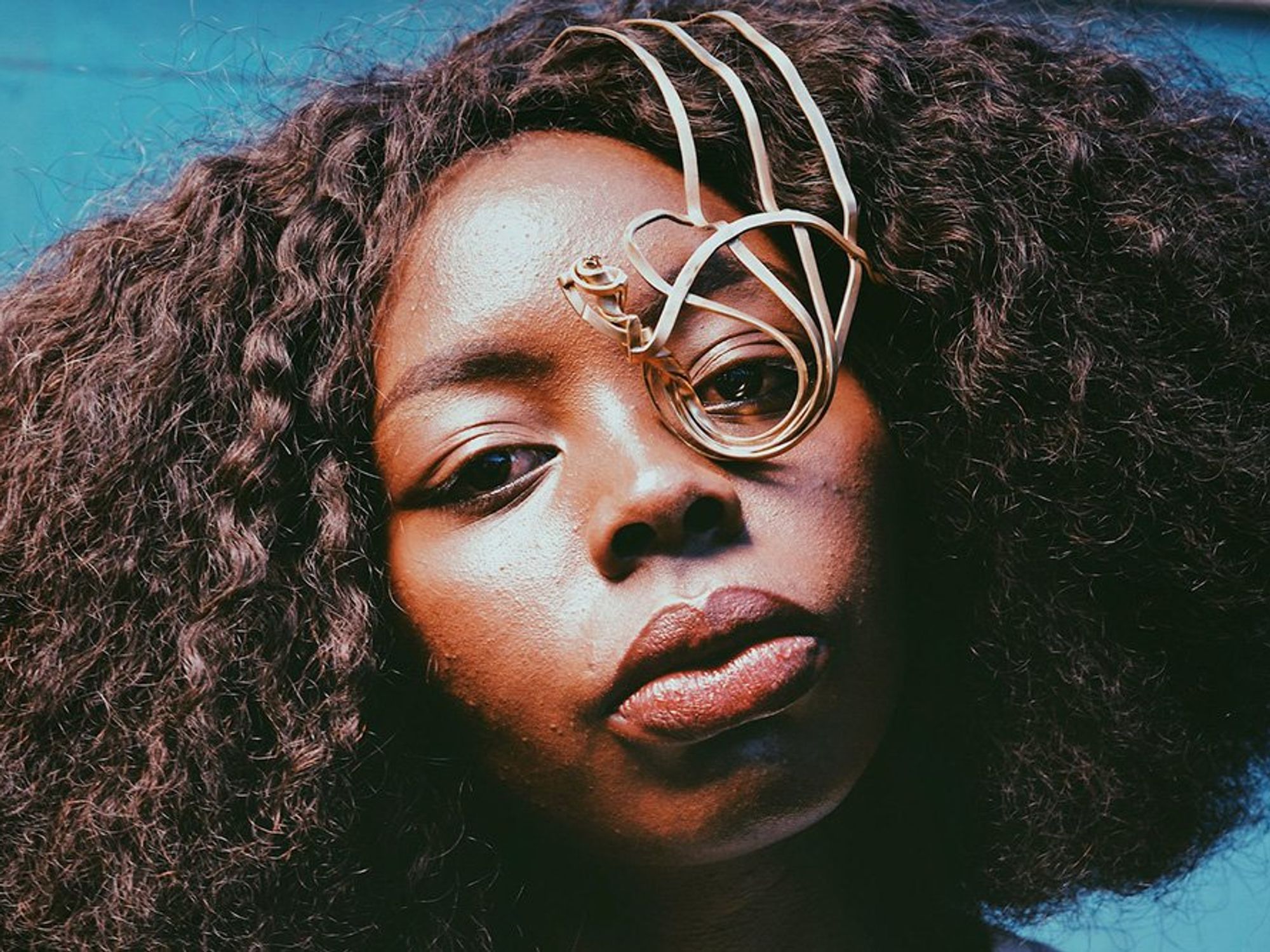A model wears an intricate piece of African jewelry over her eye.