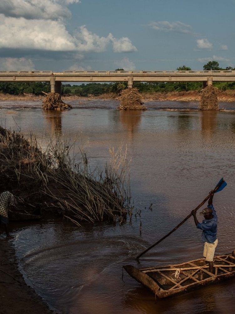 A photo of a man paddling a boat across the Lucite River after the bridge was damaged during Cyclone Idai, on March 26, 2019, outside of Magaro, Mozambique.