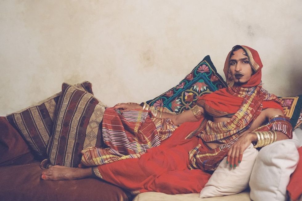 A photo of Ahmed Umar in a traditional toub sitting on a couch.
