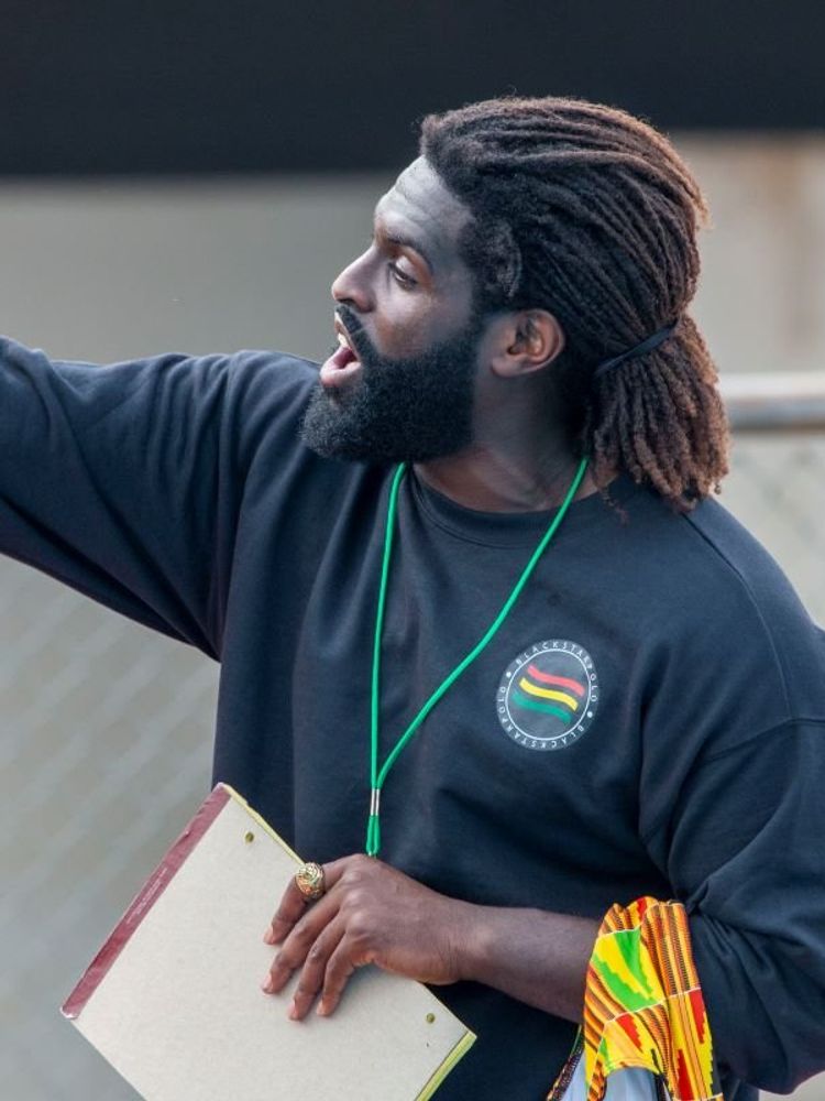 A photo of Asante Sefa-Boakye, a Black man with tied-back dreadlocks and a healthy beard, during water polo training.