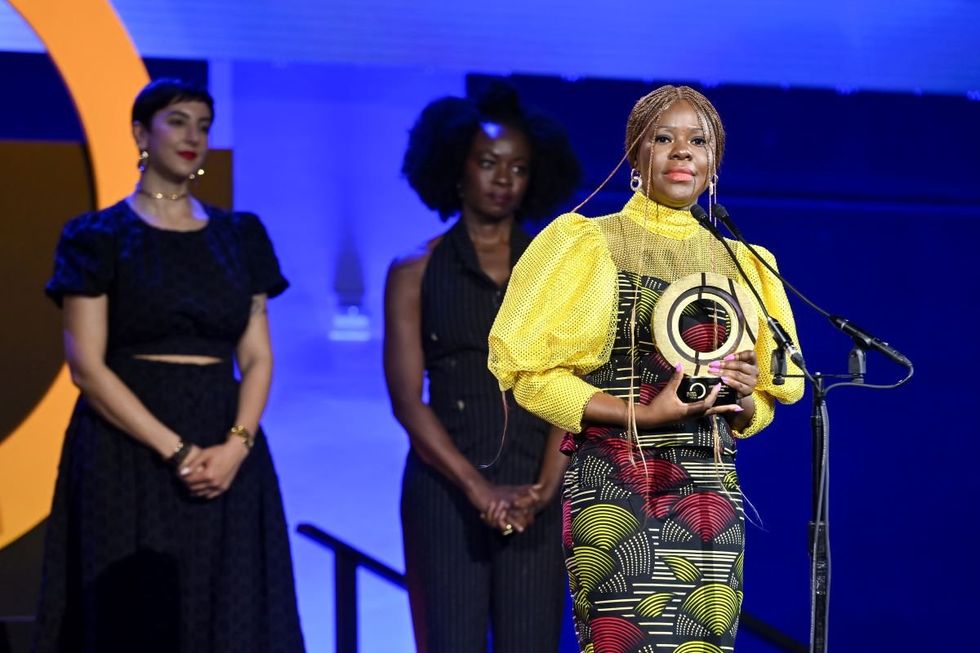 A photo of Citizen Award Recipient Lydia Charles Moyo speaking onstage (with Payzee Mahmod and Danai Gurira standing behind her) during the Global Citizen Prize event at Spring Studios on May 01, 2024 in New York City.