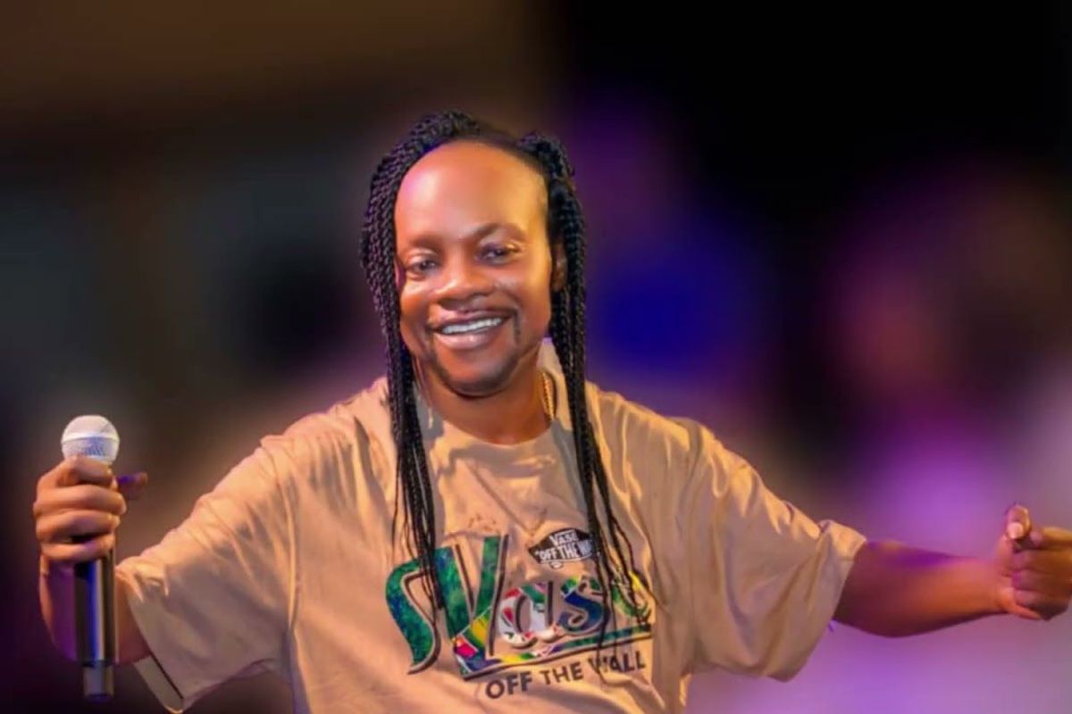 A photo of Ghanaian music legend Daddy Lumb wearing a brown t-shirt and holding a microphone.