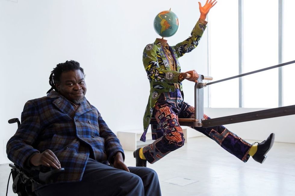 A photo of Yinka Shonibare MBE posing with his work \u201cEnd of Empire\u201d at Turner Contemporary as part of the 14-18 NOW programme.