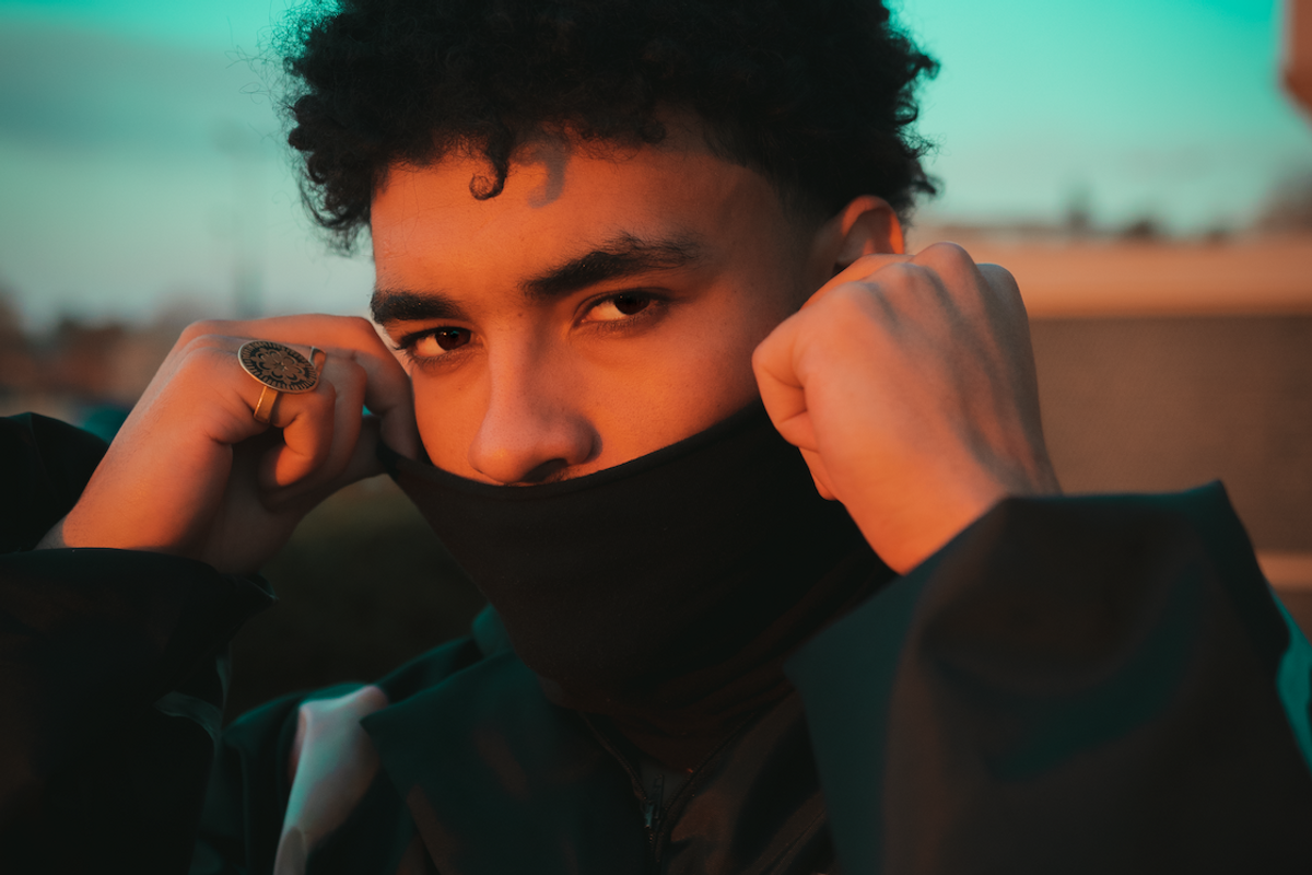 A portrait of Shane Eagle hiding his mouth with a black polo neck. 