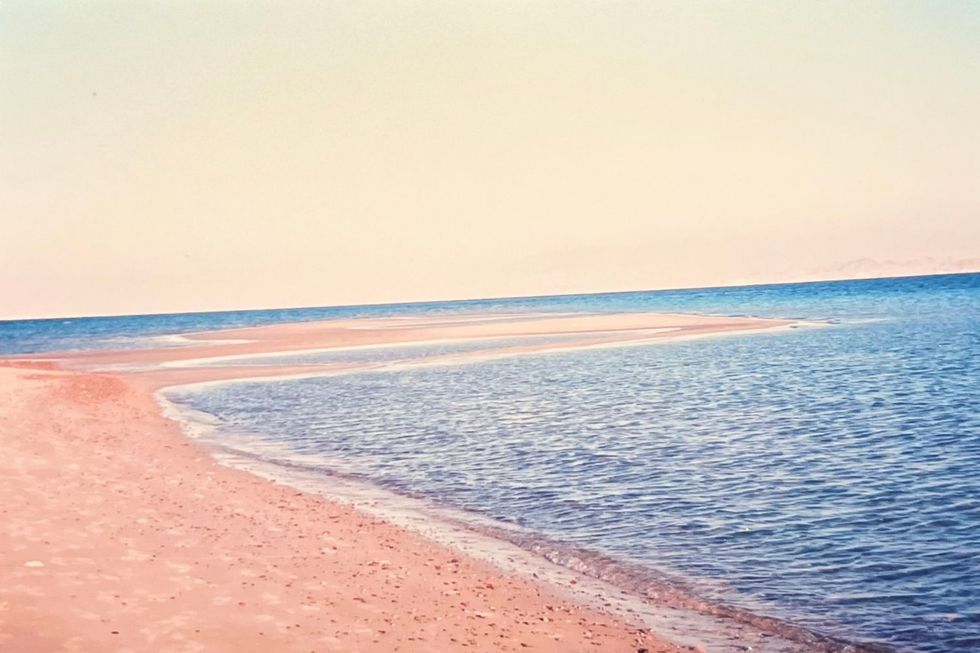 A Red Sea beach with orange sands and deep blue water.