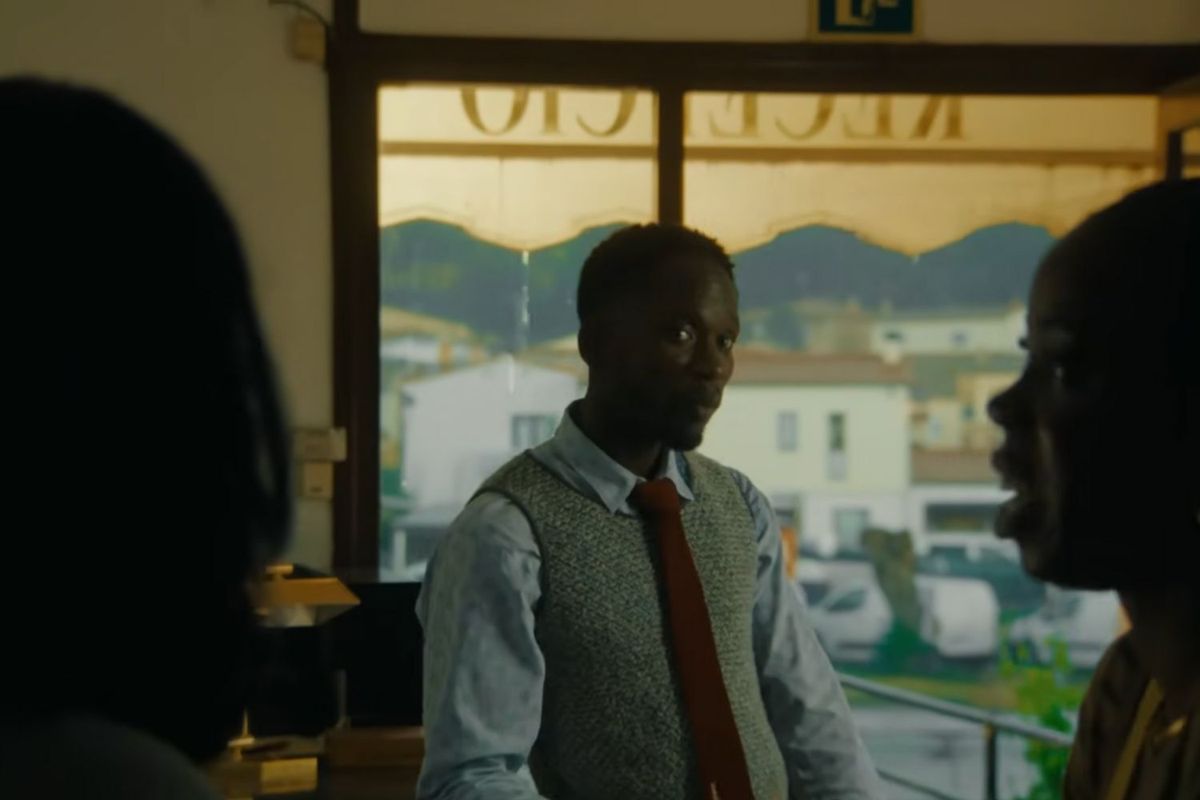 A screenshot of Mr Eazi from the “Casanova” video. He is inside a hotel, waiting for a lady to finish checking in.
