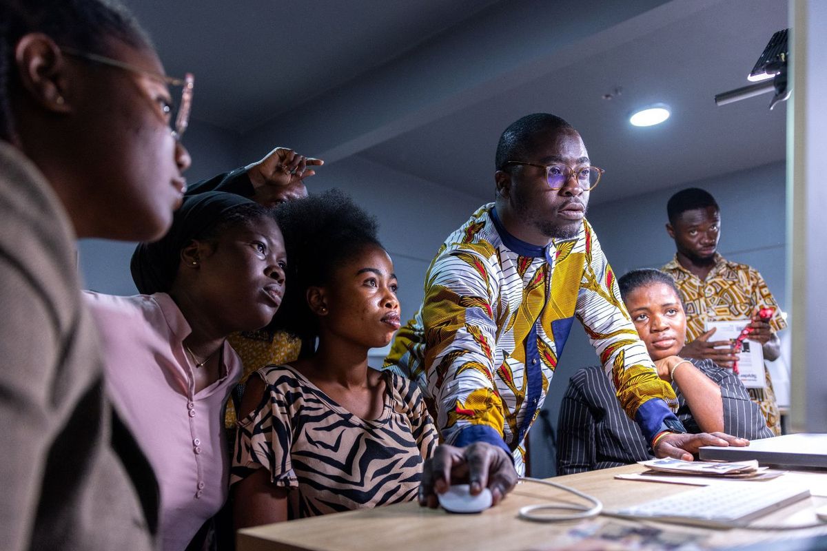 A shot of a group of people leaning close to a computer screen