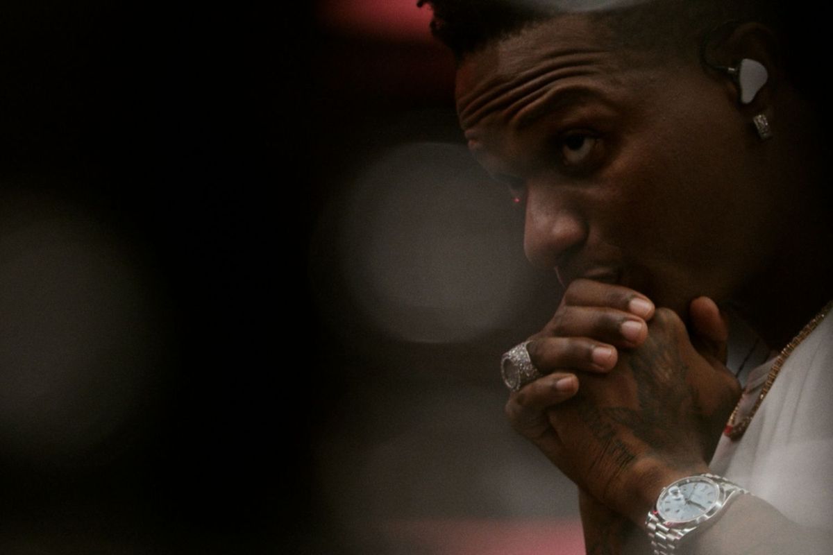 A side profile of Wizkid with his hands clasped together.