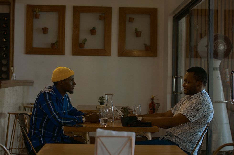A still from 'All the Colours of the World' of two men sitting in a restaurant.
