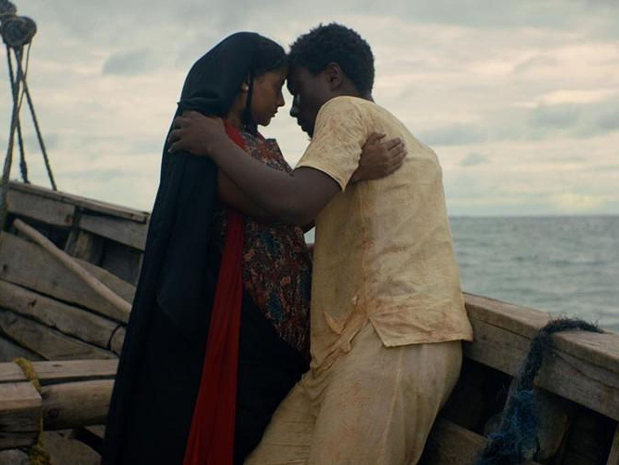 A still from the film of a man and woman holding each other on a boat