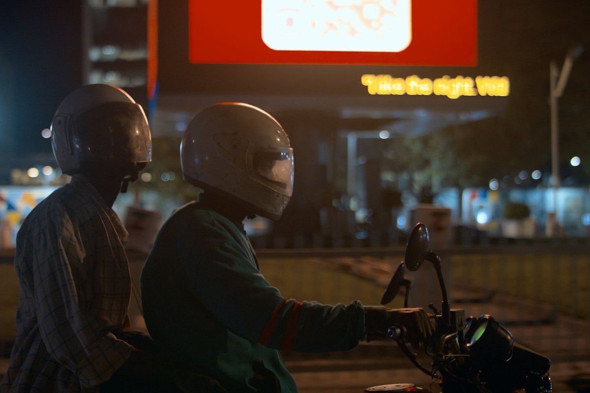 A still from the film of two men on a motorcycle wearing helmets