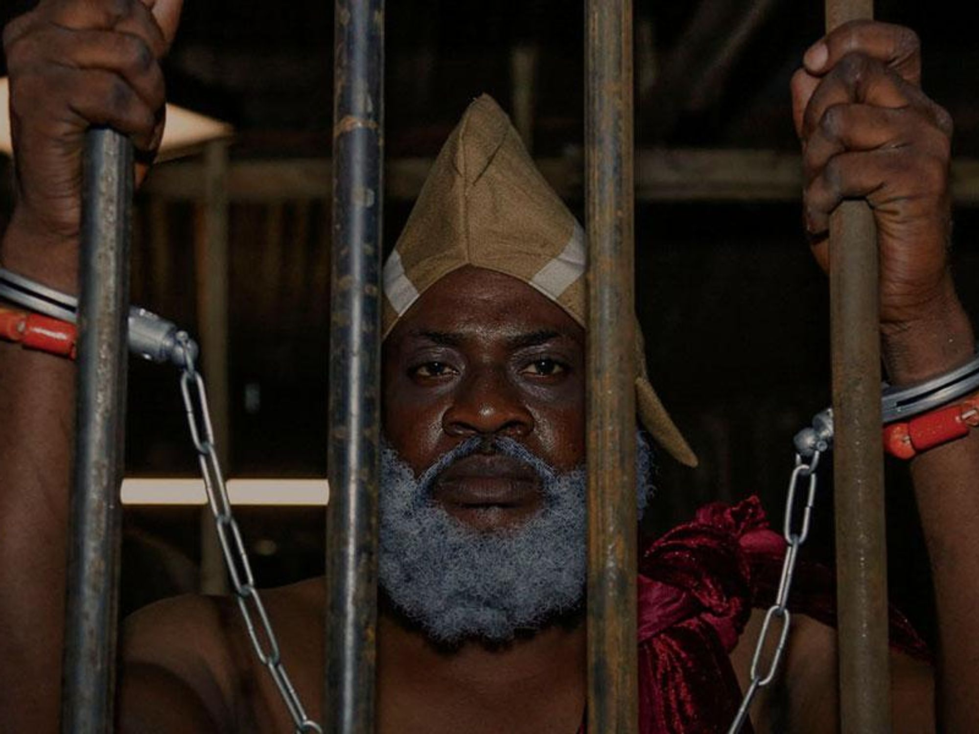 A still from the film The King's Horseman of a man in shackles behind bars