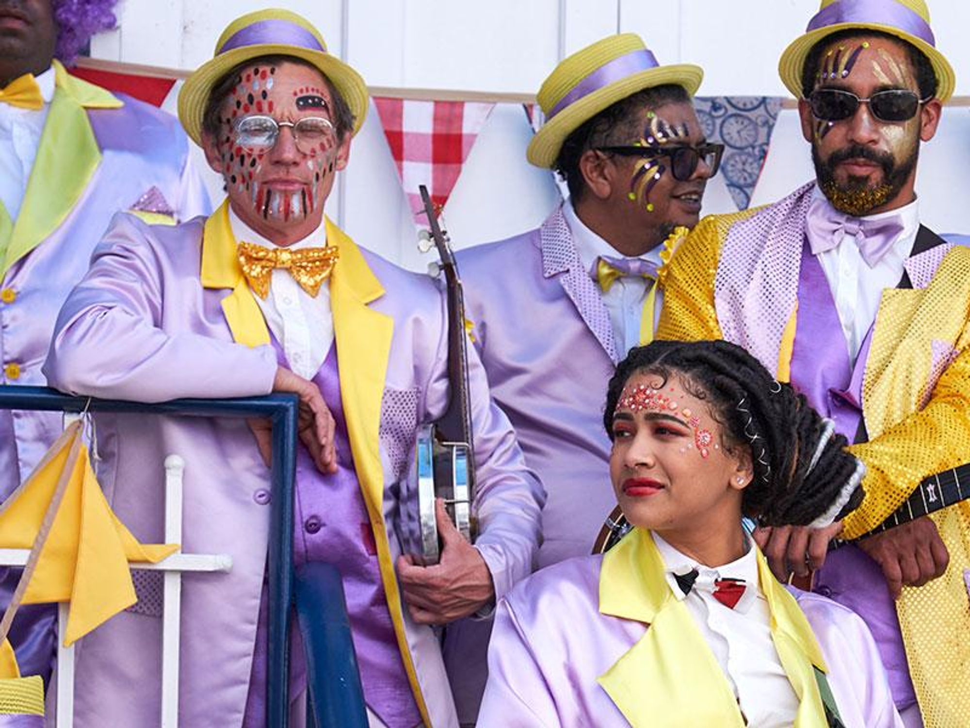 A still image from the film The Umbrella Men of minstrels in colorful outfits, waiting to play their instruments