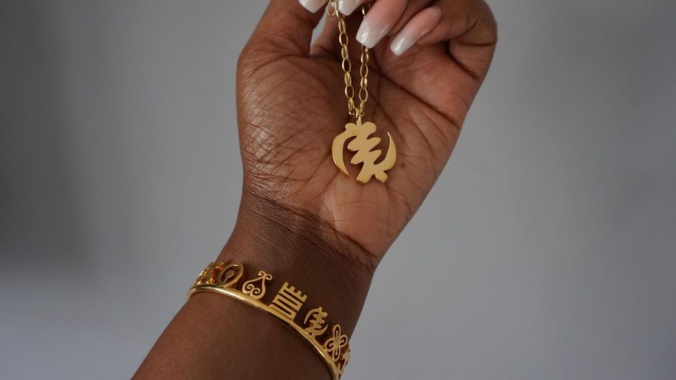 A woman's wrist with jewelry on it and in her hand is a necklace.