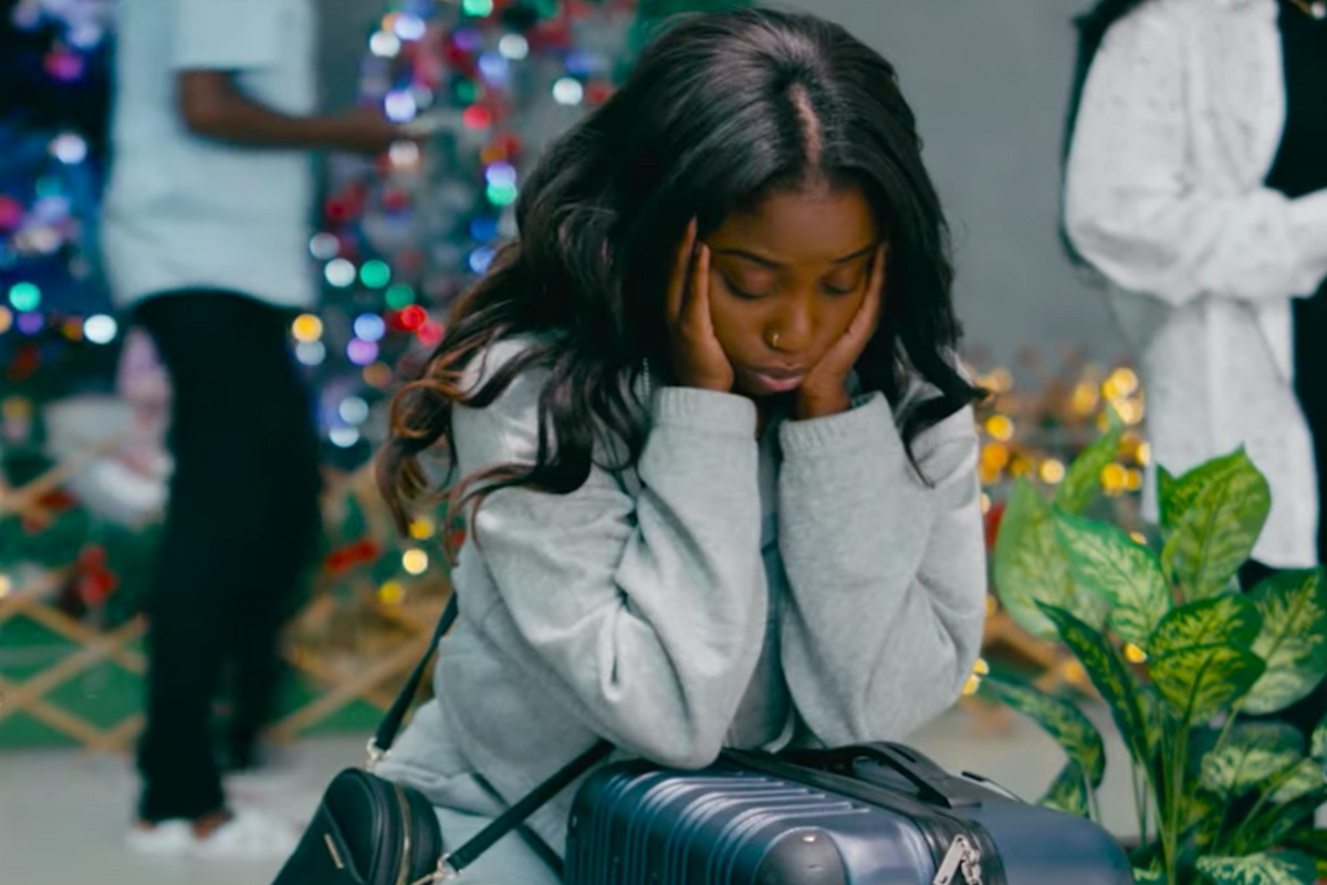 A woman sitting with her head in her hands in front of a Christmas tree.