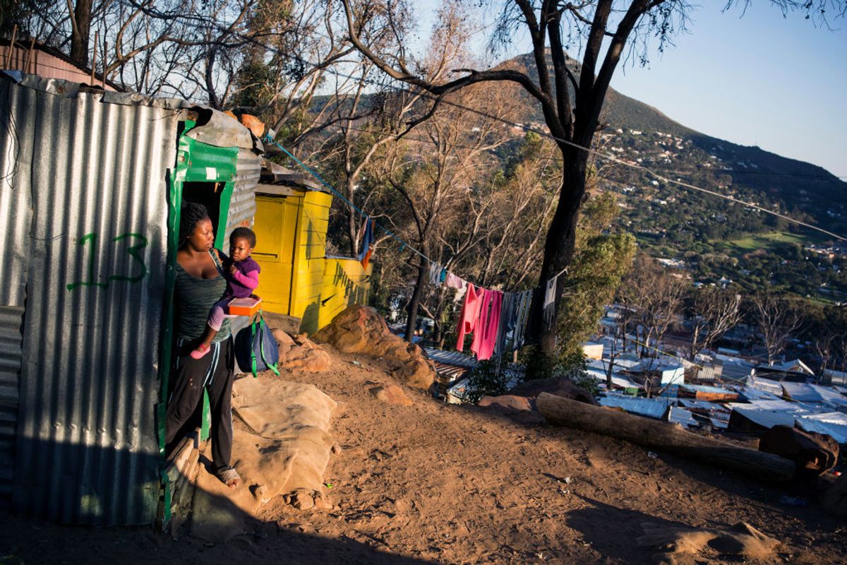 A women carries her child outside her shack at Imizamo Yethu settlement.