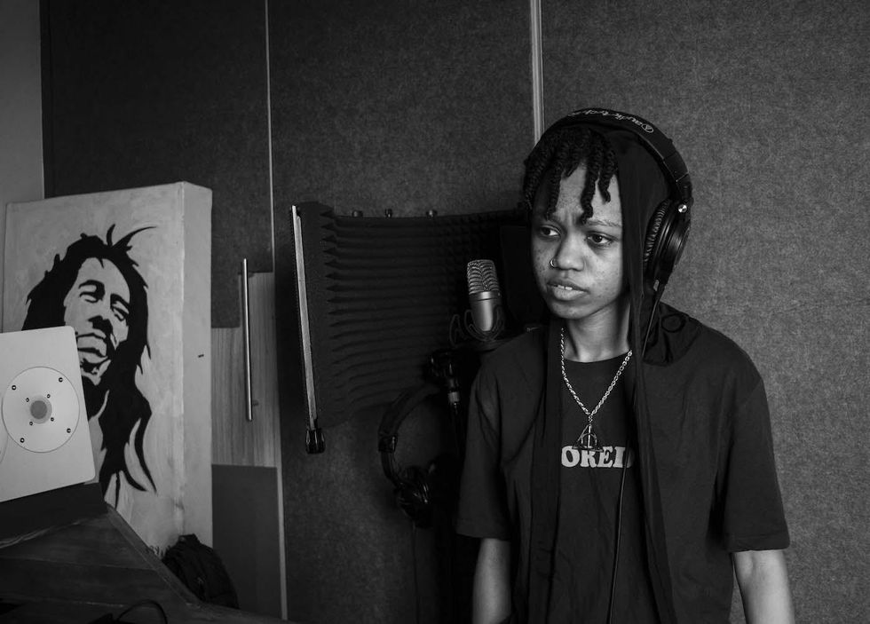 A young woman with dreadlocks in the recording booth in the studio. 