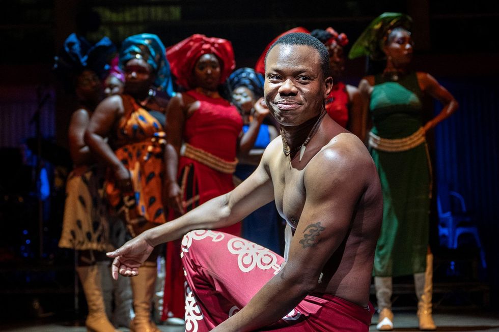Actor Duain Richmond kneeling at the front of the stage, smiling, during the Fela production.