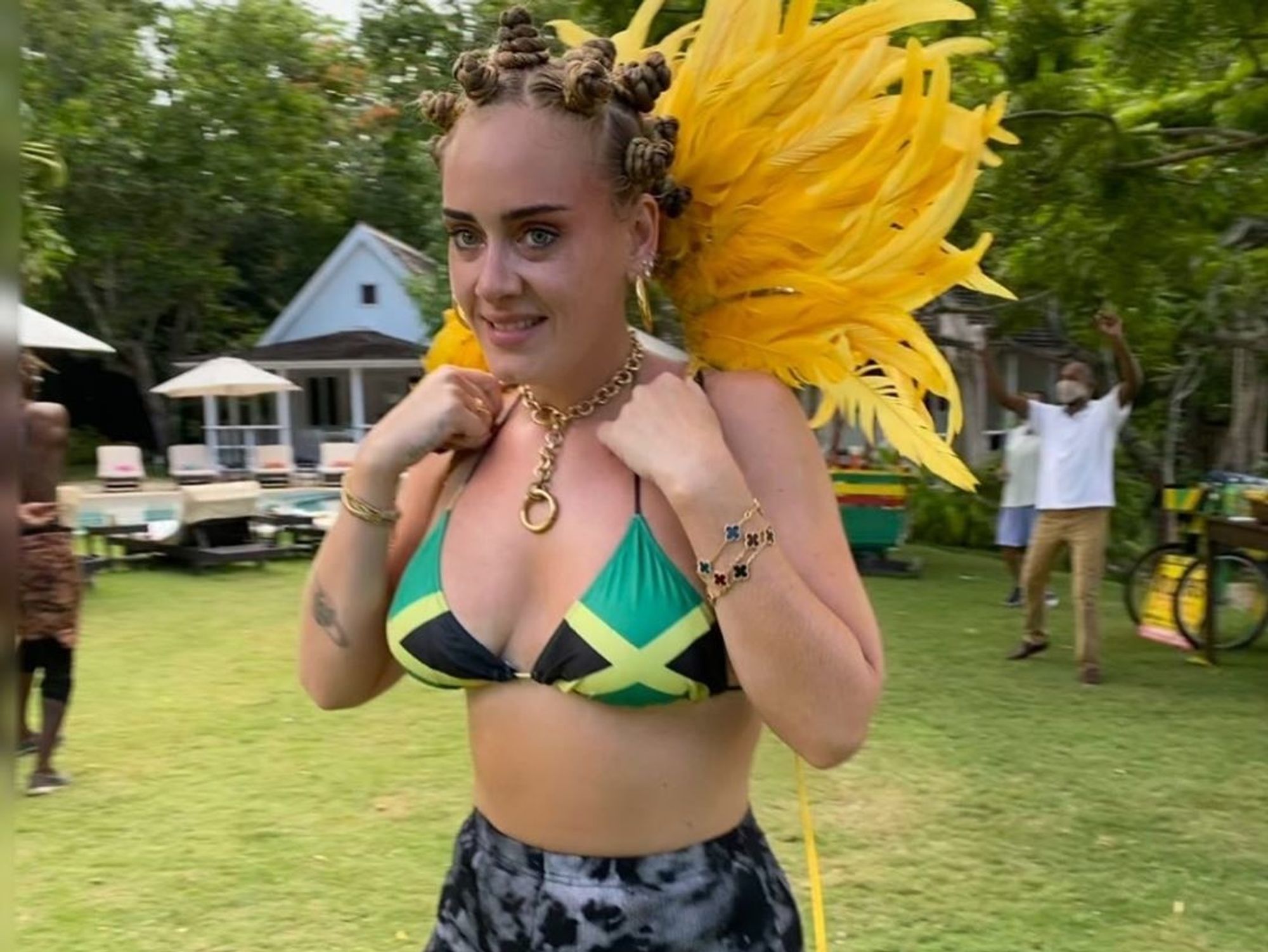 Adele in Jamaican bikini, yellow feathers and Bantu knot hairstyle.