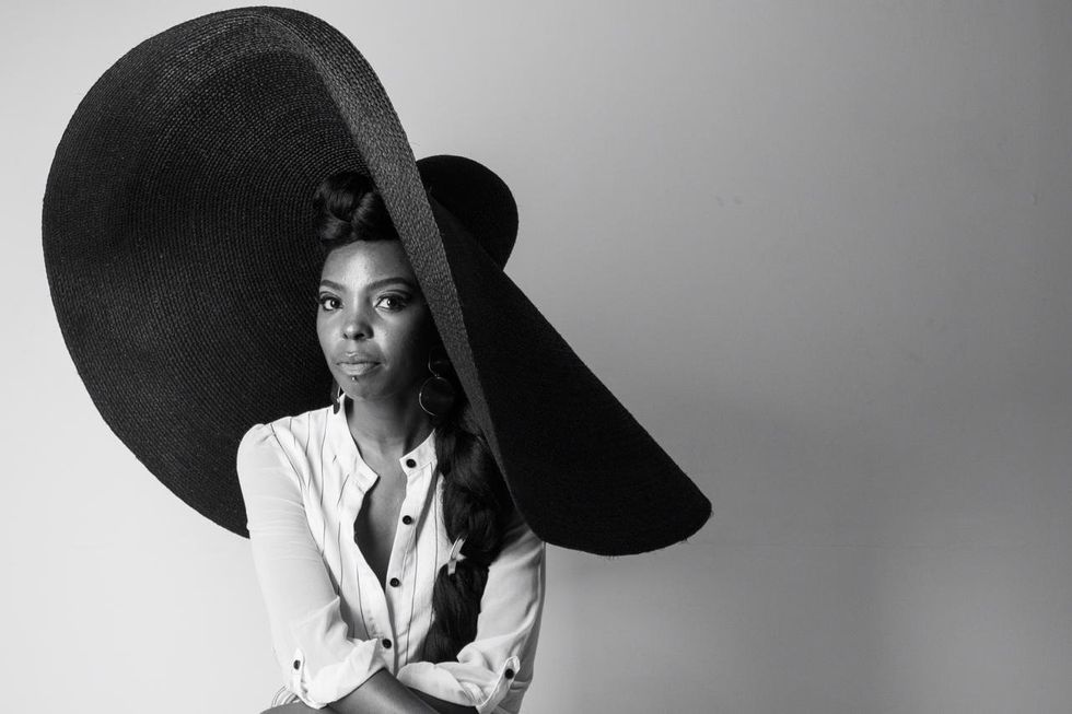Adelle Onyango poses for a photo wearing a giant wide-brimmed hat. 