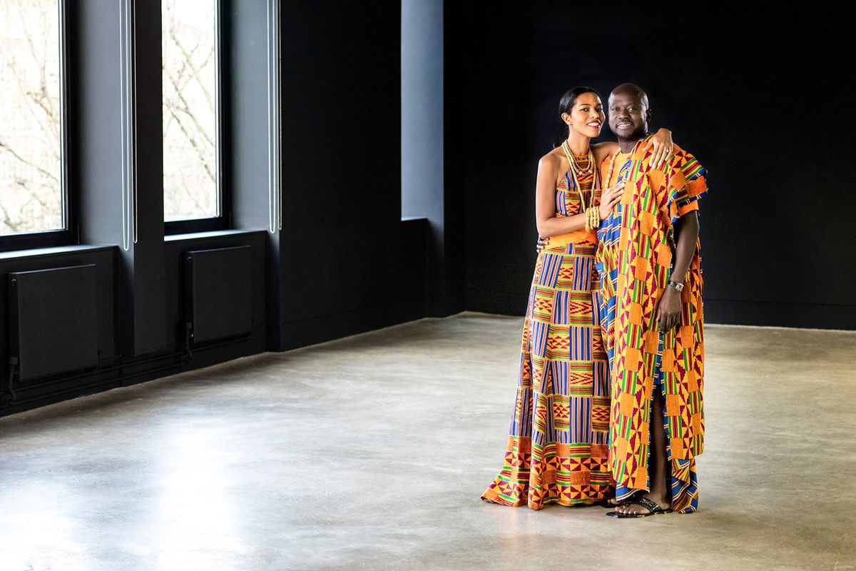 An image of a couple standing in a room wearing traditional Ghanaian outfits.