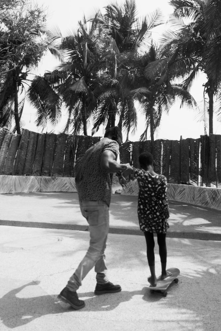 An image of a man helping a young woman on a skateboard