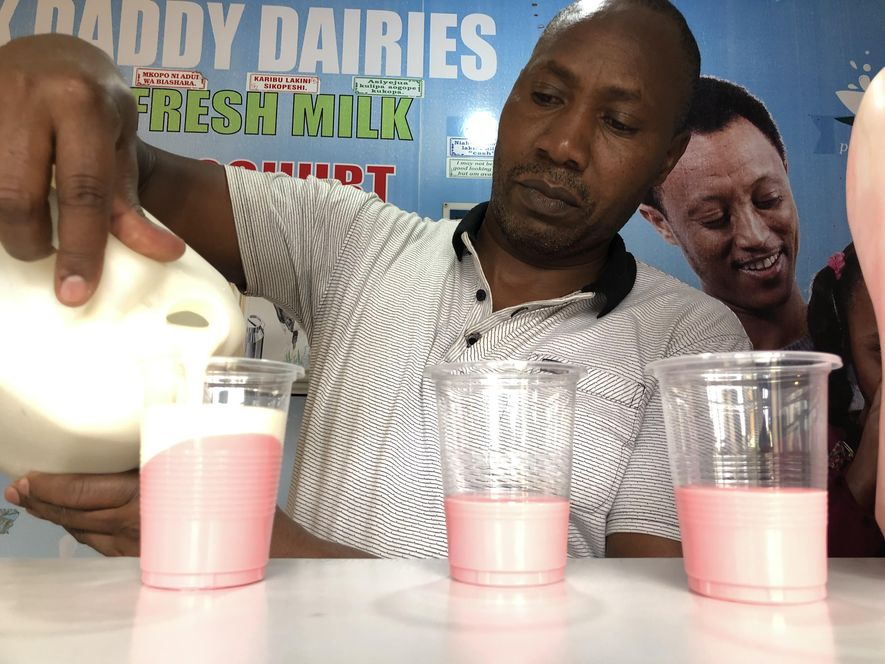 An image of a man pouring a yogurt drink in Kibera.