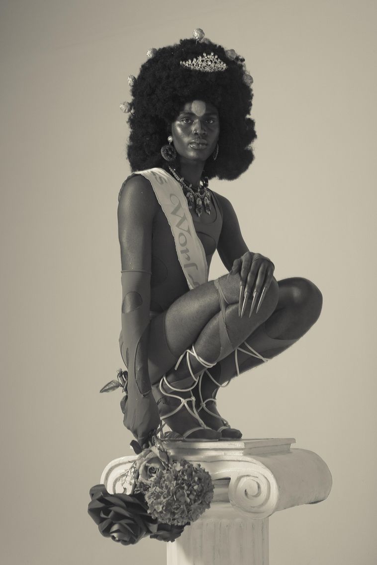 An image of a man wearing a sash standing on a pillar in a artwork by Daniel Obasi