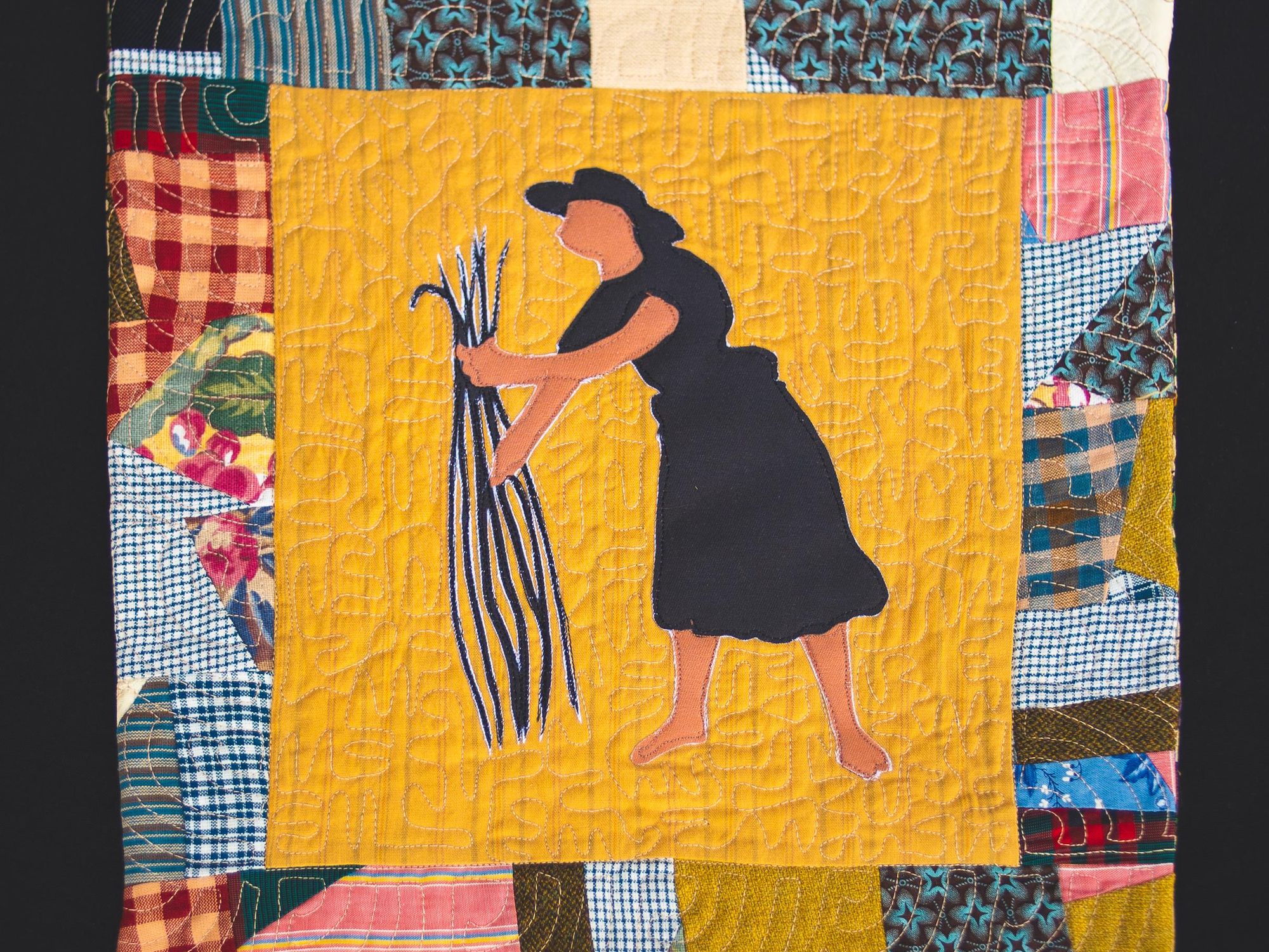 An image of a quilt patch with a woman standing in a rice patch