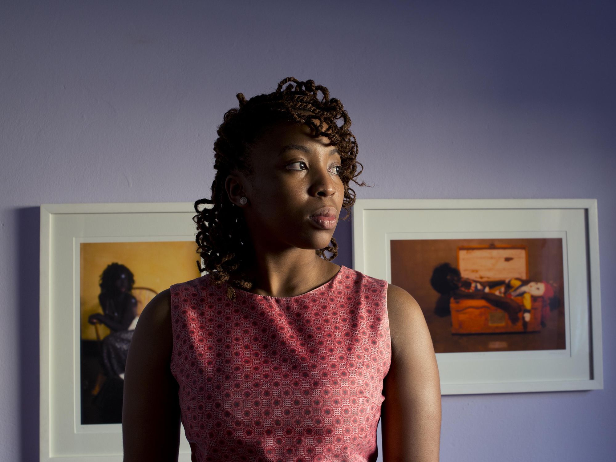 An image of artist ​Lebohang Kganye standing in front of photographs