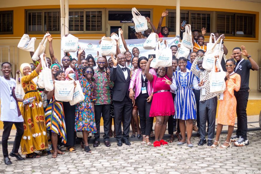 An image of attendees of this year\u2019s AfroCuration with their arms up in the air, smiling as they take a group photo.