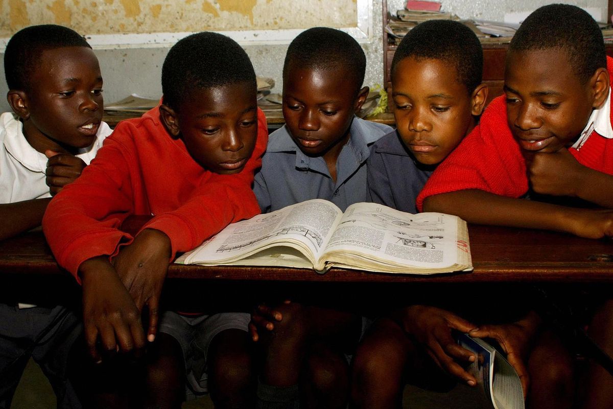 An image of five Zimbabwean pupils at a primary school reading from the same book.