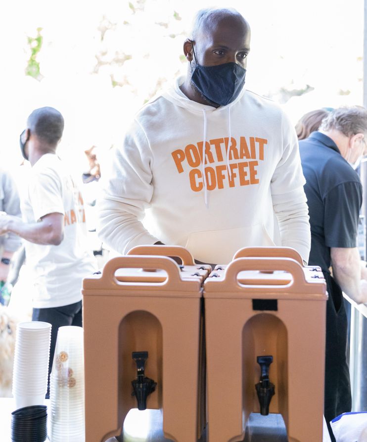 An image of John Onwuchekwa standing in front of a coffee dispenser