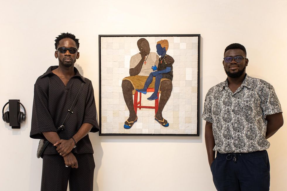 An image of Mr Eazi and Tesprit standing in front of Tesprit\u2019s painting.