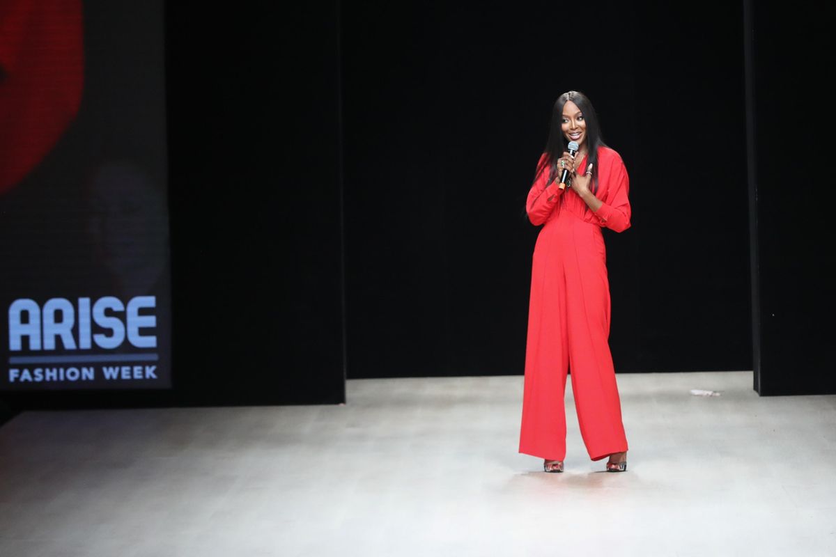 An image of Naomi Campbell with a microphone in her hand, talking to the audience at Arise Fashion Week in 2019.
