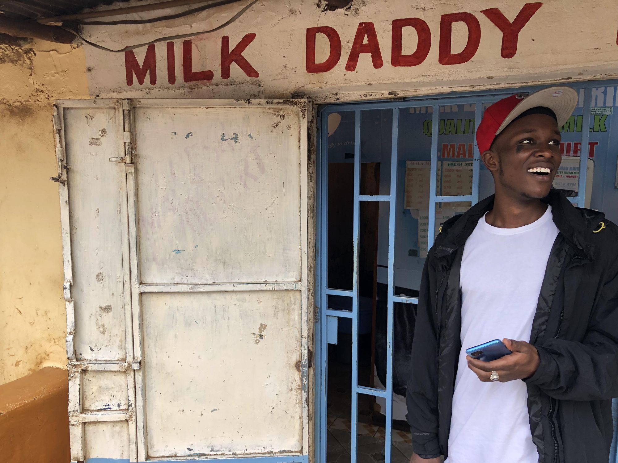 An image of rapper Big Yasa standing in front of a food stall in Kibera. 