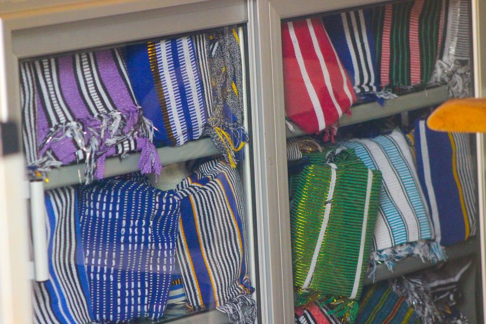 An image of rolls of kente cloth on shelves of a store.