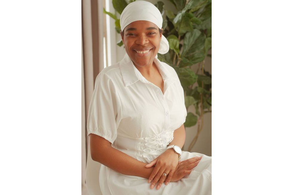  An image of the author, who has her hair in a white wrap, and is looking at the camera, smiling.